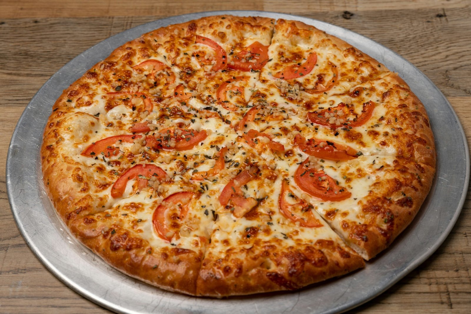 A pizza sitting on top of a pizza pan on top of a wooden table